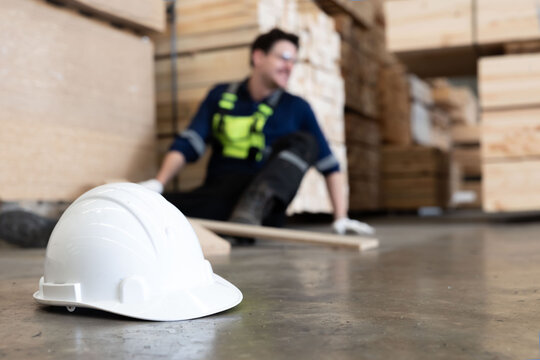 Close-up on white hard hat with blurred injured factory worker on the floor