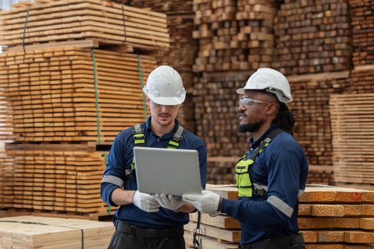 Workers discuss tasks in a warehouse with pallets stacked high in the background