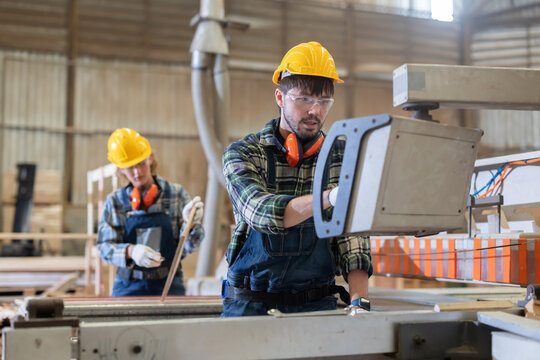 Worker measures wood in a warehouse during the day while wearing safety gear