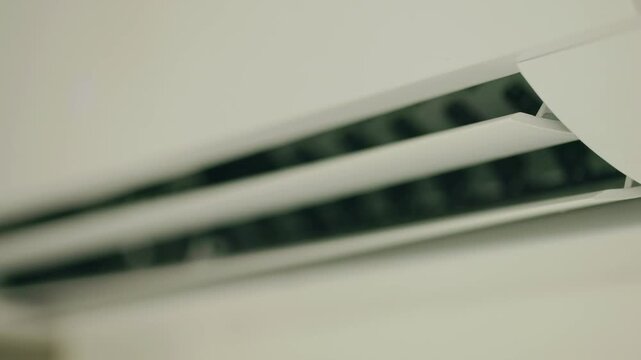 Close up of white air conditioner louvers moving slowly on white background static shot.