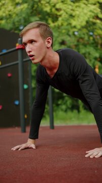 Man doing push-ups at an outdoor fitness ground. close up of a Young sporty man doing push-ups at an outside gym. Athlete doing classic floor push-ups during a street workout session.
