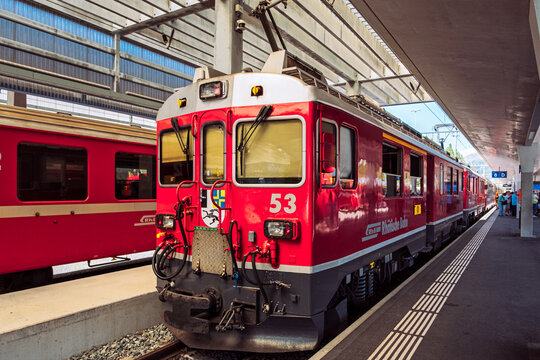 St Moritz Switzerland - August 14 2021:Red train locomotive of Rhaetische Bahn parked at St Moritz railway station in Graubunden Switzerland with platform and overhead power lines