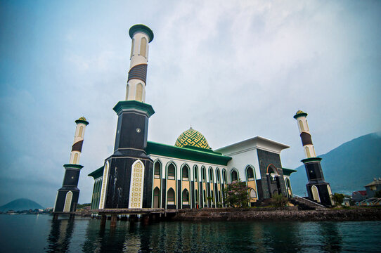 Scenic view of Al Munawwar Floating Mosque on the coast of Ternate City, North Maluku, featuring green domes and tall minarets by the sea.