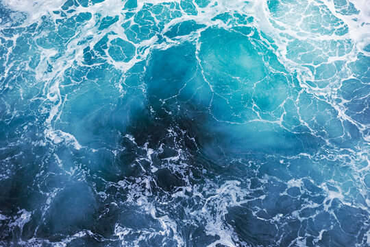 Blue ocean surface with gentle ripples and sparkling sunlight reflections, creating a calm, serene natural background with beautiful water texture.