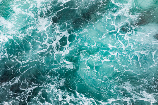 Ocean surface with gentle ripples and sparkling sunlight reflections, creating a calm, serene natural background with beautiful water texture.