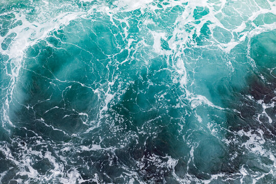 Ocean surface with gentle ripples and sparkling sunlight reflections, creating a calm, serene natural background with beautiful water texture.