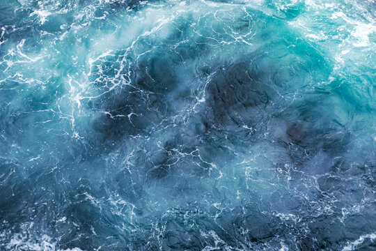 Blue ocean surface with gentle ripples and sparkling sunlight reflections, creating a calm, serene natural background with beautiful water texture.