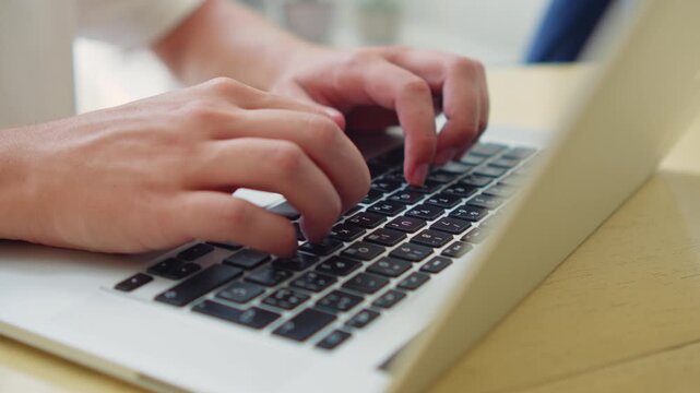 Man typing on a laptop close up. Person working on a computer at a desk.