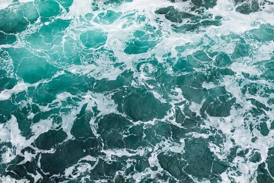 Ocean surface with gentle ripples and sparkling sunlight reflections, creating a calm, serene natural background with beautiful water texture.