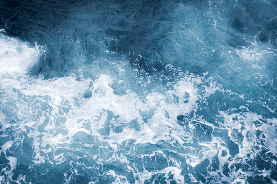 Blue ocean surface with gentle ripples and sparkling sunlight reflections, creating a calm, serene natural background with beautiful water texture.