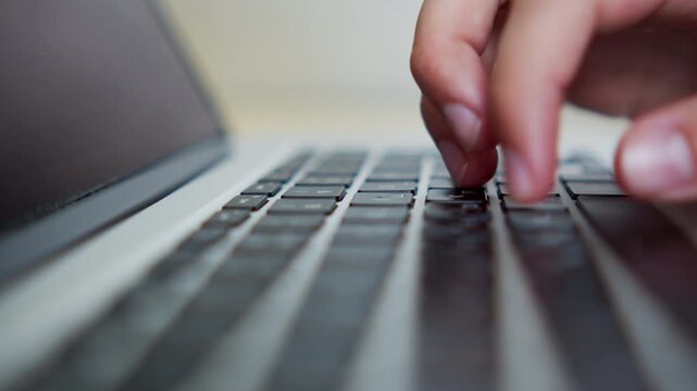 Macro shot of a person fast typing on a laptop keyboard. Man fast typing text on a keyboard.