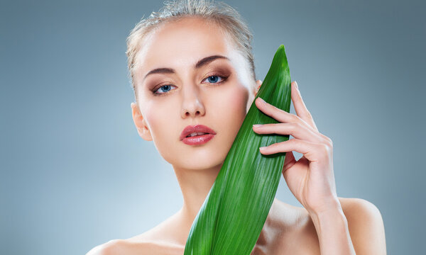 Beautiful Woman with Natural Makeup Holding Green Leaf for Skincare