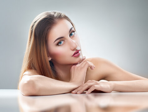 Elegant Woman with Natural Makeup Posing Gracefully on Glossy Surface
