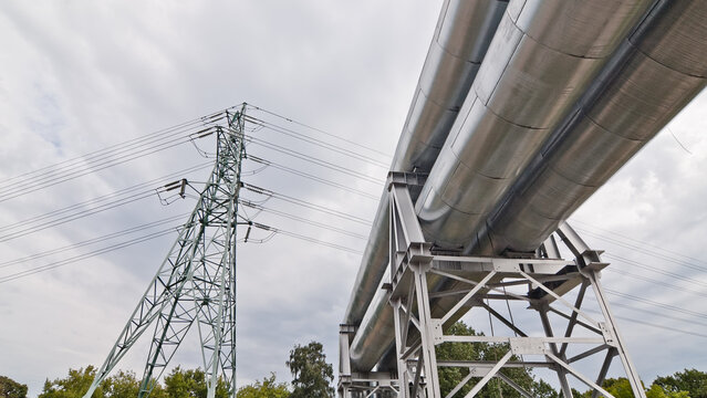 a pipeline and a power transmission tower against a gray sky