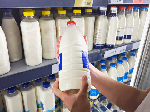 Shopper Choosing Large Milk Bottle in Supermarket Dairy Section