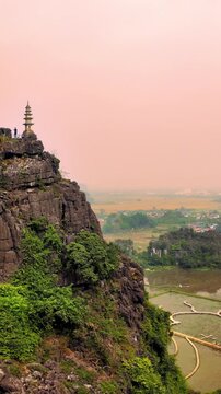 Pan Shot from Mountain Peak to Scenic Valley Landscape With Rice Fields and Village in Ninh Binh During Soft Afternoon Haze