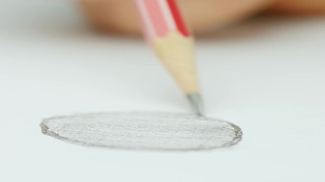 Macro view of person hand drawing circle on white paper with wooden pencil in slow motion closeup footage.