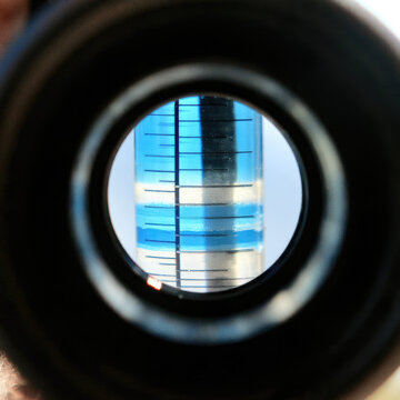 Refractometer scale viewed through circular optical eyepiece, showing sharp blue and white sugar level boundary with lens reflection and detailed macro texture