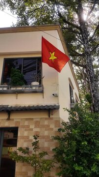 Tracking Shot of Vietnamese National Flag Waving Outside Residential Building in Ho Chi Minh City Vietnam during Sunny Daylight