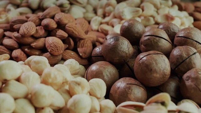 Assortment of delicious and healthy nuts including almonds pistachios macadamia and cashews slowly moving.