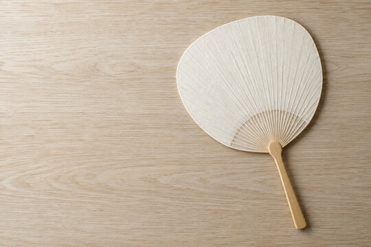 Plain Japanese uchiwa hand fan on wooden table with copy space