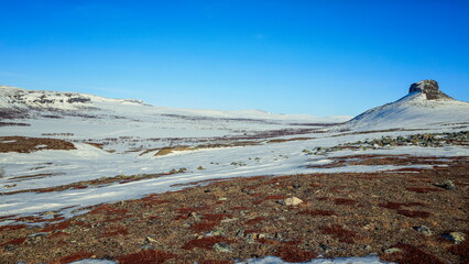 Enontekiö, Finland - 10.04.2023: Snowy arctic tundra landscape with a rocky peak under a clear blue sky in Lapland © Andrei