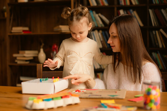 mother teaching toddler daughter educational color sorting game at home