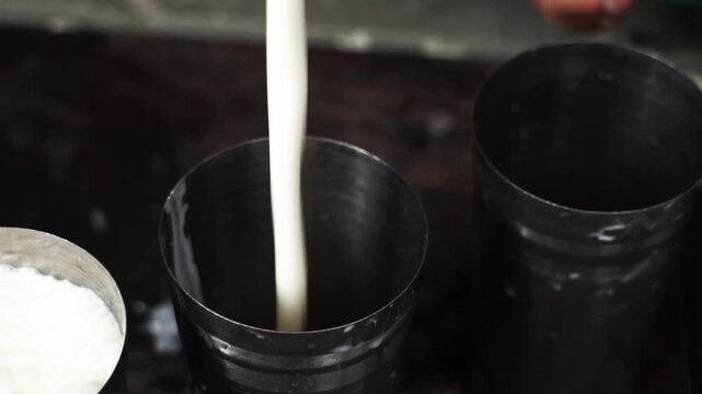 Fresh creamy lassi being poured and stirred in a glass.
