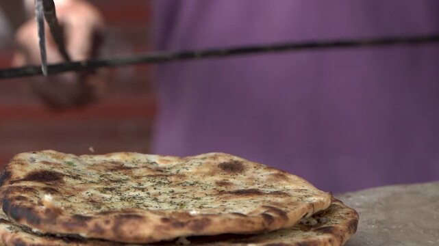 Freshly cooked flat bread or parantha being taken out from a traditional tandoor.