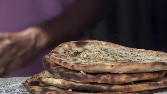 Freshly cooked flat bread or parantha being taken out from a traditional tandoor.