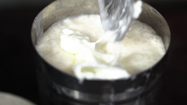 Fresh creamy malai being placed on traditional Indian lassi.