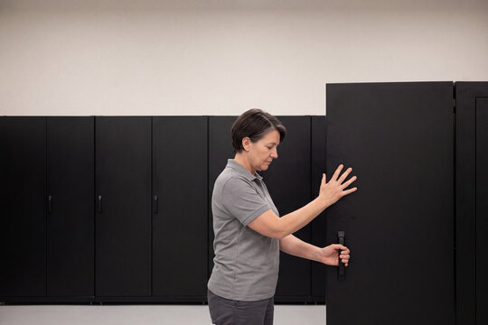 Woman data center technician closing a server cabinet door