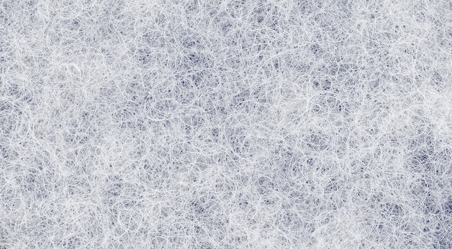 Nonwoven curls in white fibrous paper with overlapping strands and translucent openings, a textured sheet background for drawing and collage with loose fibers throughout the surface