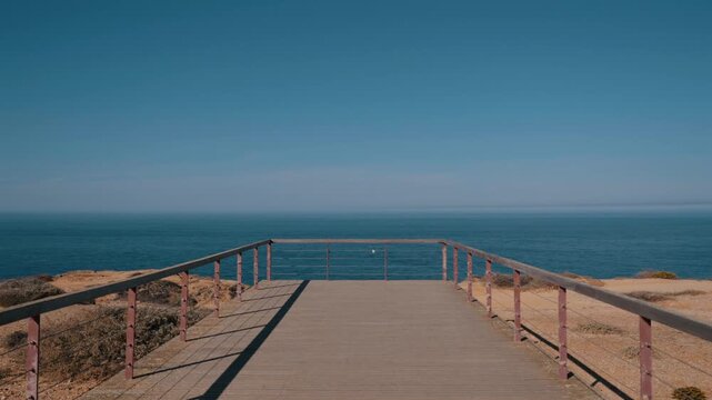 Empty wooden viewpoint deck with railing overlooking the Atlantic Ocean, Cabo Sardao, Portugal