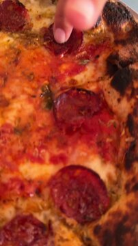 Low tilted close-up of pepperoni pizza slice with blistered charred crust and bubbling melted cheese, served on restaurant table