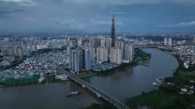 Blue-hour aerial panorama of Landmark 81 district, dense high-rise housing and a broad river bend in Ho Chi Minh City from an elevated drone perspective