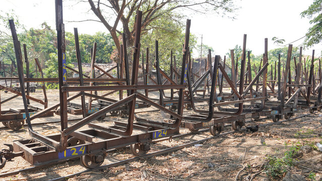 Empty traditional rusty metal sugarcane rail cars parked on narrow tracks at historical Rendeng Sugar Mill in Kudus, Central Java, Indonesia, used for transporting sugar cane during harvest.