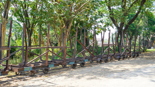 Empty traditional rusty metal sugarcane rail cars parked on narrow tracks at historical Rendeng Sugar Mill in Kudus, Central Java, Indonesia, used for transporting sugar cane during harvest.