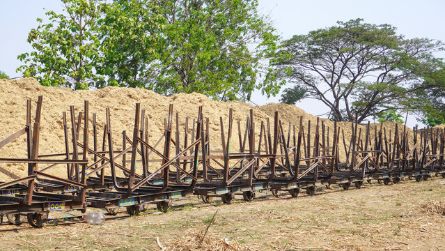 Empty traditional rusty metal sugarcane rail cars parked on narrow tracks at historical Rendeng Sugar Mill in Kudus, Central Java, Indonesia, used for transporting sugar cane during harvest.