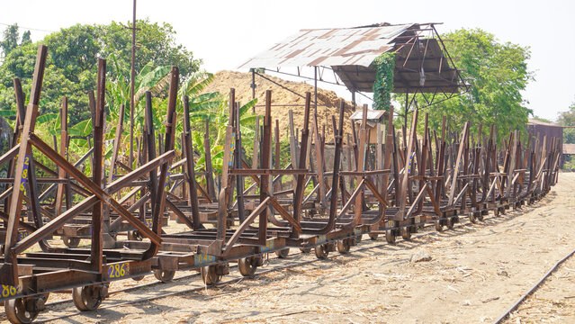 Empty traditional rusty metal sugarcane rail cars parked on narrow tracks at historical Rendeng Sugar Mill in Kudus, Central Java, Indonesia, used for transporting sugar cane during harvest.