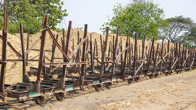 Empty traditional rusty metal sugarcane rail cars parked on narrow tracks at historical Rendeng Sugar Mill in Kudus, Central Java, Indonesia, used for transporting sugar cane during harvest.