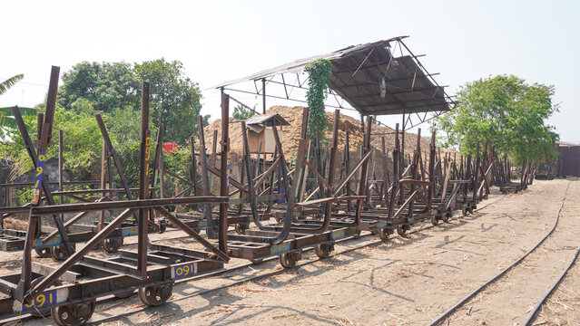 Empty traditional rusty metal sugarcane rail cars parked on narrow tracks at historical Rendeng Sugar Mill in Kudus, Central Java, Indonesia, used for transporting sugar cane during harvest.