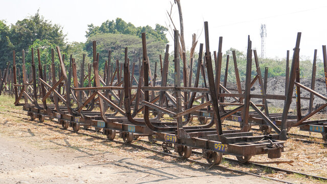 Empty traditional rusty metal sugarcane rail cars parked on narrow tracks at historical Rendeng Sugar Mill in Kudus, Central Java, Indonesia, used for transporting sugar cane during harvest.