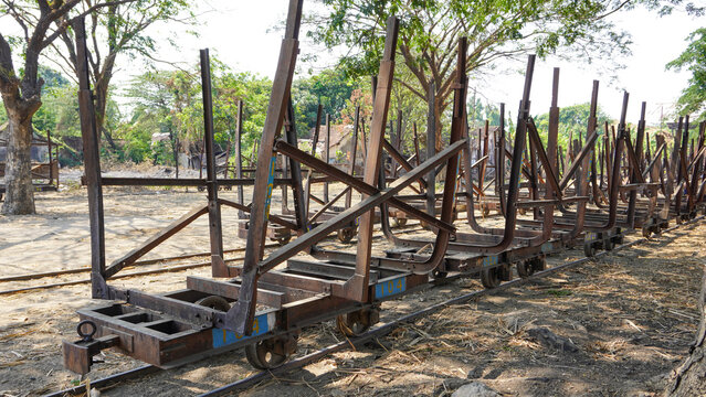 Empty traditional rusty metal sugarcane rail cars parked on narrow tracks at historical Rendeng Sugar Mill in Kudus, Central Java, Indonesia, used for transporting sugar cane during harvest.