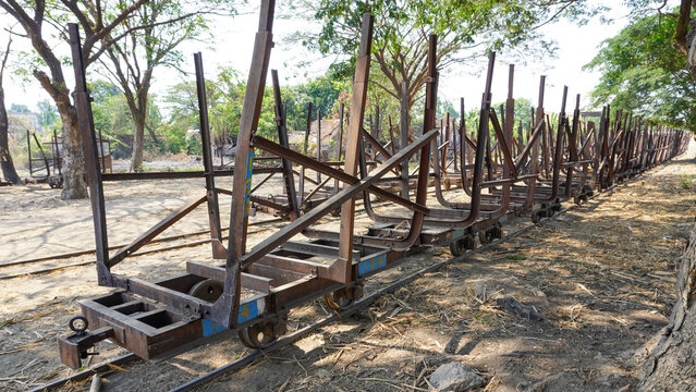 Empty traditional rusty metal sugarcane rail cars parked on narrow tracks at historical Rendeng Sugar Mill in Kudus, Central Java, Indonesia, used for transporting sugar cane during harvest.