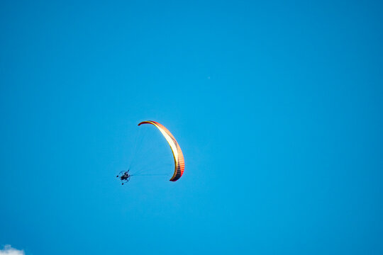Paraglider soars through vibrant blue sky