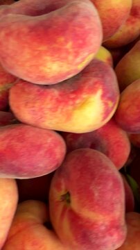 Close-up of stacked peaches and oranges in dark slatted crate with warm soft highlights, dimpled peel texture, and abundant fresh produce display in grocery market setting