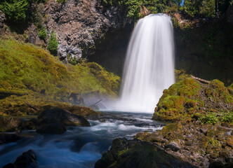 Sahalie Falls cascades powerfully down basalt cliffs in Oregons Willamette National Forest, creating mist among mossy rocks © steheap