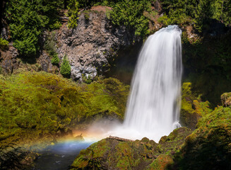 Fototapeta premium Sahalie Falls cascades powerfully down basalt cliffs in Oregons Willamette National Forest, creating mist and a rainbow.