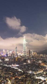 Time Lapse of clouds and the moon moving above the skyline of Taipei Taiwan at night. Vertical Video.